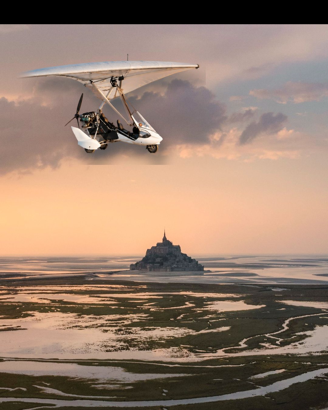 Un ULM en vol au-dessus de la baie, le Mont-Saint-Michel en contrebas